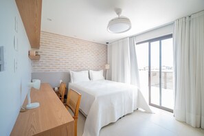 Una habitación de hotel moderna con una cama grande, un escritorio de madera, una silla y vistas de la ciudad a través de un amplio ventanal.