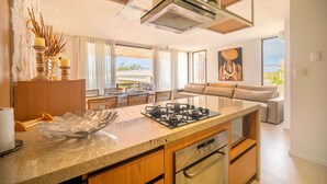 A modern kitchen with a central island, stainless steel appliances, and a dining area with a view.