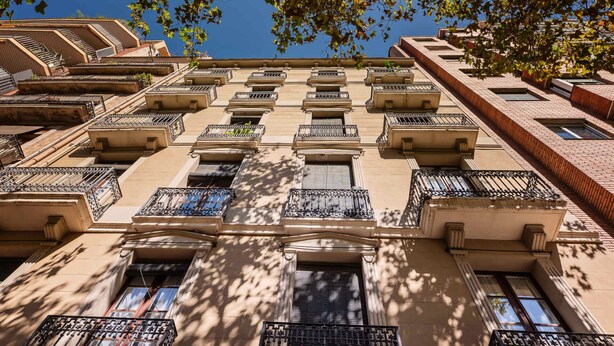 A multi-story building with a symmetrical facade, featuring evenly spaced balconies with metal railings and windows.