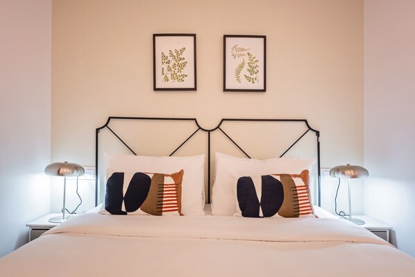 A neatly made bed with two pillows, a headboard, and two bedside lamps.