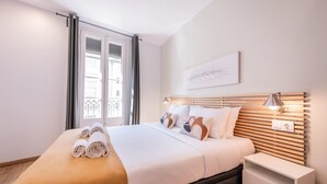 Ein ordentlich bezogenes Bett mit aufgerollten Handtüchern, einer Nachttischlampe und einem Nachttisch.