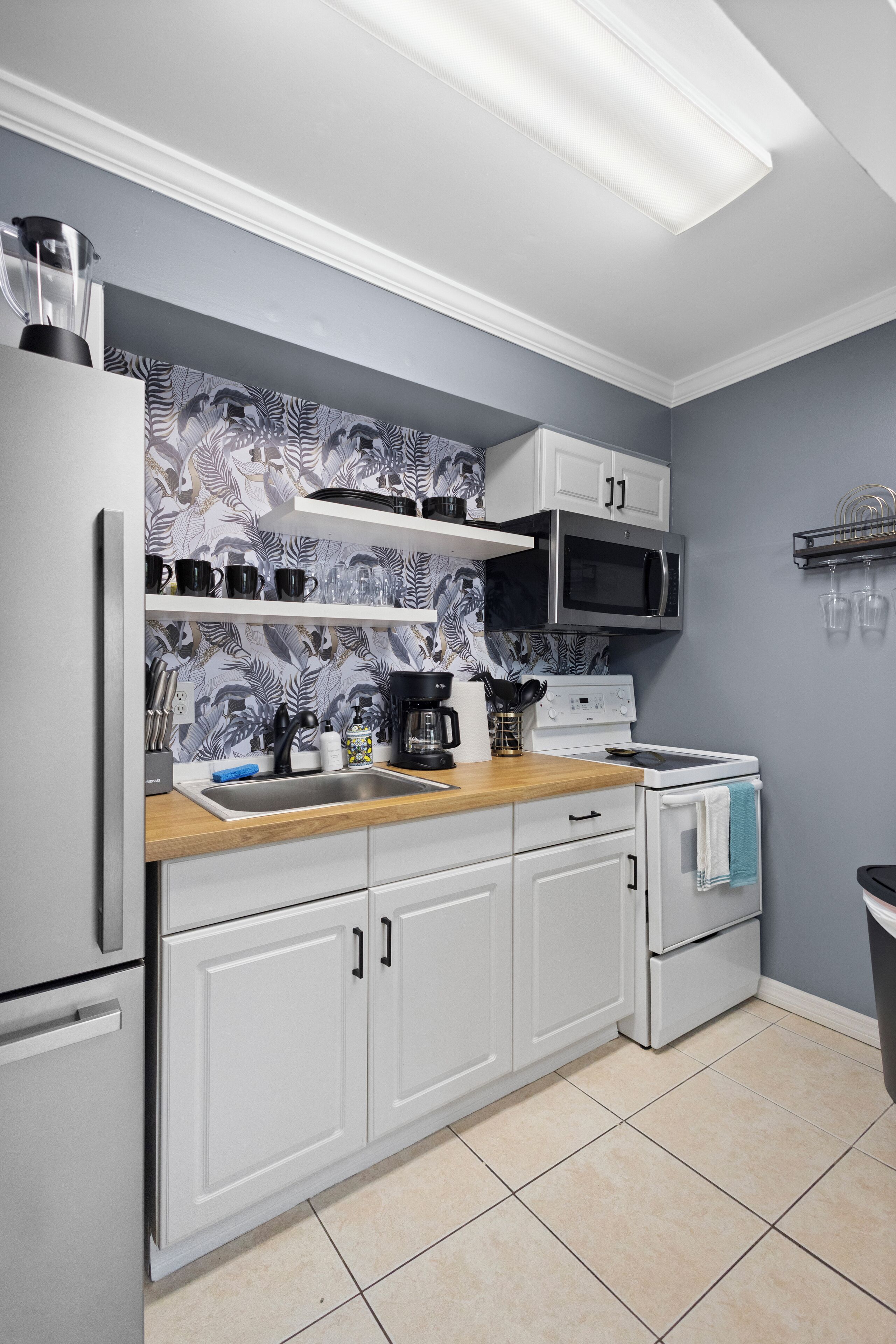 A modern kitchen with white cabinets, a microwave, a stove, and a sink.