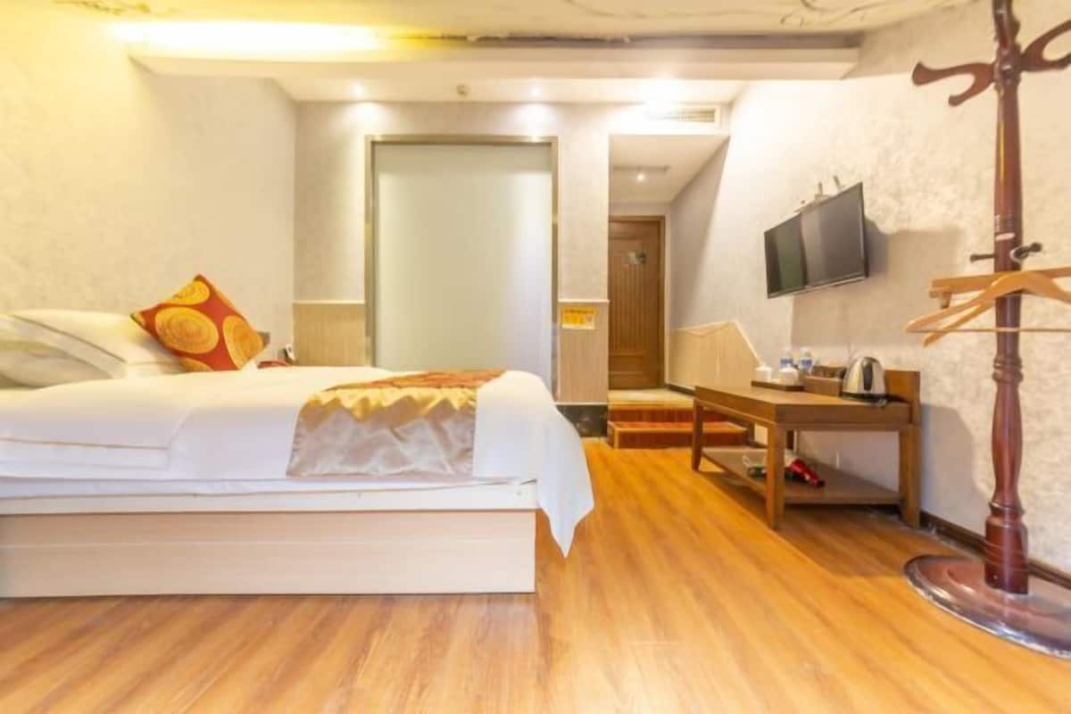 Ein Hotelzimmer mit Bett, Nachttisch, Fernseher und Kleiderhaken.