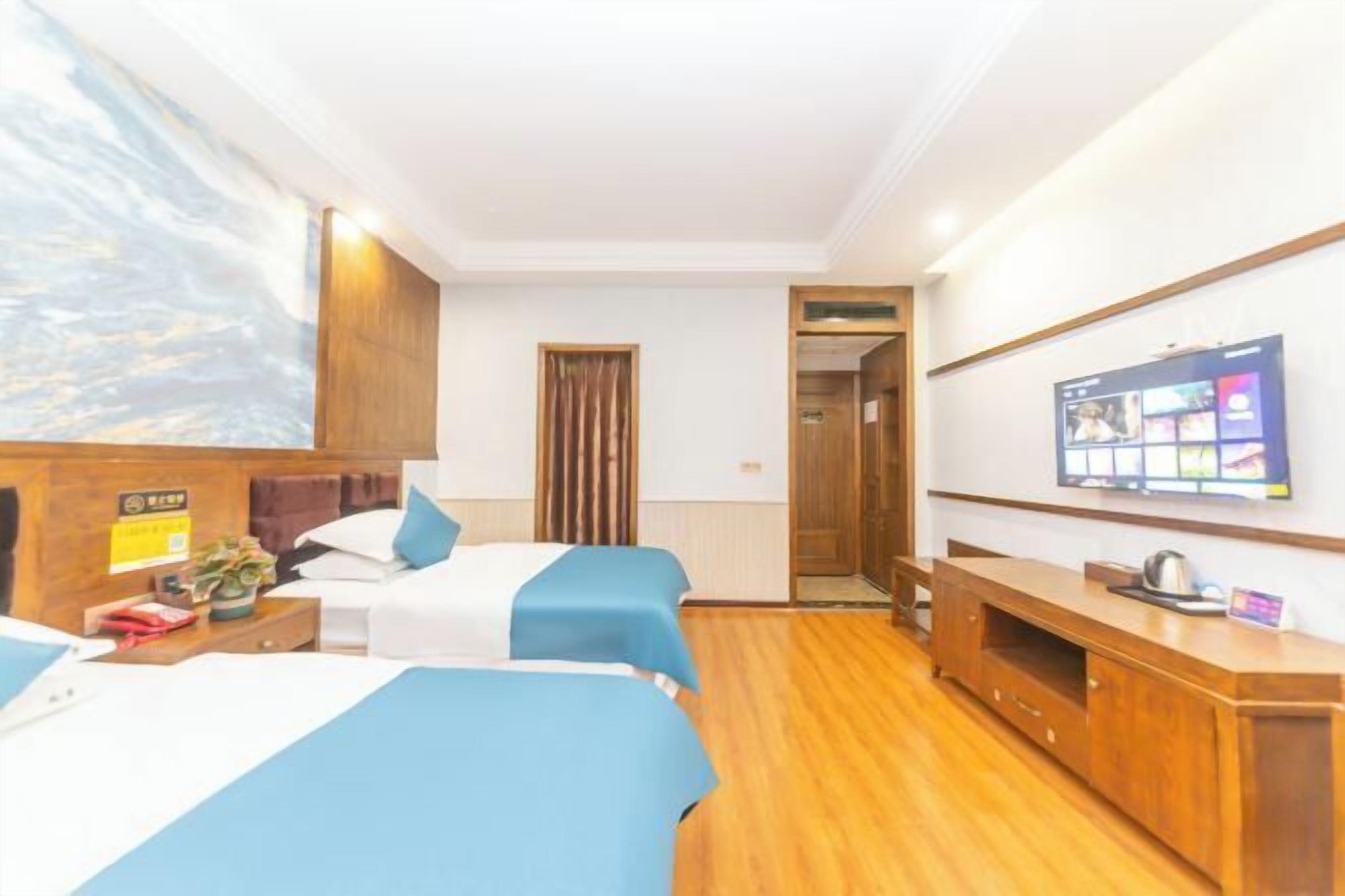 A hotel room with two beds, a TV, a wooden cabinet, and a painting on the wall.