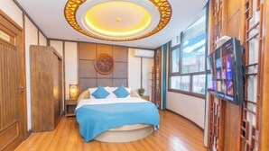 A hotel room with a round bed, a ceiling light fixture, wooden furniture, and a large window. - Xijingli Hotel (Yuzhong Ancient City) (Langzhong)
