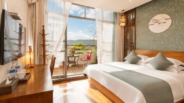 A hotel room with a bed, a desk, a TV, and a balcony with a view. - Xijingli Hotel (Yuzhong Ancient City) (Langzhong)