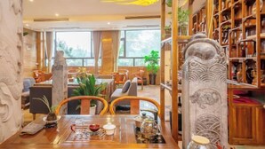 A restaurant with a wooden interior, a statue, and a bookshelf. - Xijingli Hotel (Yuzhong Ancient City) (Langzhong)
