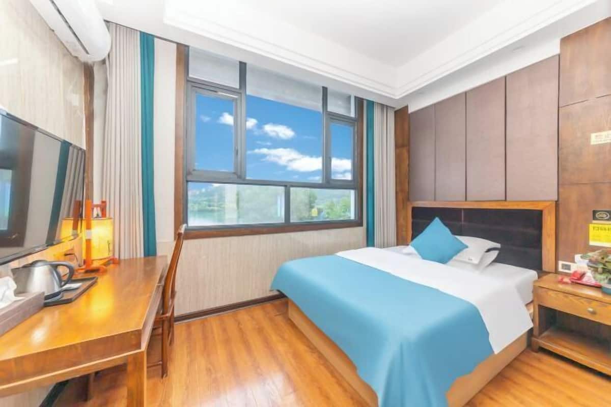 Ein Hotelzimmer mit Bett, Schreibtisch, Stuhl, Fernseher und einem Fenster mit Blick.
