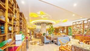 A hotel lobby with wooden bookshelves, a central column, seating areas, and a decorative ceiling. - Xijingli Hotel (Yuzhong Ancient City) (Langzhong)