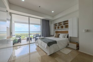 Relax in a spacious room with a large bed and sliding glass door leading to a balcony with outdoor seating.