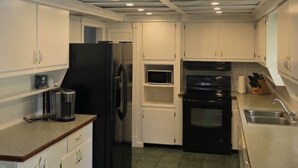A compact kitchen with white cabinets, a black refrigerator, a microwave, and a stove.