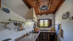 A kitchen with a granite countertop, hanging utensils, and a window with a view.