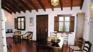 A dining area with wooden furniture, a tiled floor, and a ceiling with exposed beams.