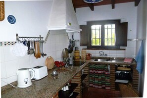 Una cocina con estufa, pileta y diferentes utensilios.
