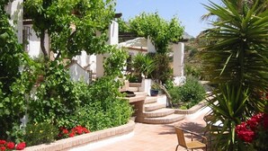 A courtyard with a chair, a potted plant, and a staircase leading to a building.