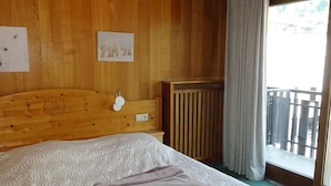 Une pièce aux murs lambrissés, avec un lit, une petite table et une fenêtre donnant sur un beau paysage.