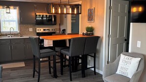 A modern kitchen with dark cabinets, a wooden dining table, and a pendant light.