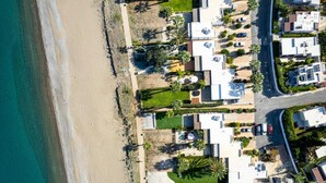 Ein Luftbild eines Küstenresorts mit mehreren Villen, einem Sandstrand und Palmen.