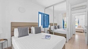 Ein modernes Hotelzimmer mit einem großen Bett, einem Nachttisch, einem Spiegel und Blick ins Freie.