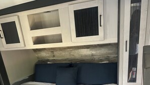 A bedroom with a bed, dark blue bedding, and a white headboard.