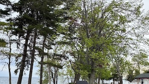 Un espace extérieur aménagé au bord du lac, avec des chaises Adirondack, un foyer et une terrasse en bois.