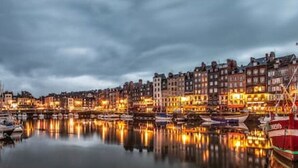A waterfront cityscape with historic buildings and a prominent red boat docked at the pier. - Lovely Traditional Manor new 2025 Pool (Group Up to 26x) (Mesnil-en-Ouche)