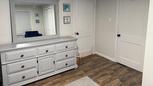 A white dresser with multiple drawers and a large mirror. There are two doors in the room, one with a handle and one with a lock. - Charming 2-bdrm home in Little Rock with WiFi and AC (Little Rock)