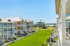 A beachfront property with multiple-story buildings, a well-maintained lawn, and a view of the ocean. - Serenity Cove Beachside Village Galveston - Lux 4bd Sleeps 12 w/ Beach Access (Galveston)