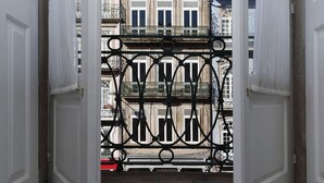 A view through a wrought iron gate of a building with multiple balconies and windows.