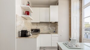 A compact kitchen with white cabinets, a marble backsplash, and a window with a view.