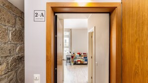 A hallway leading to a 2-A apartment with a stone wall, a wooden door frame, and a view into the living area with a sofa and a table.