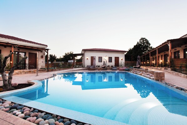 A swimming pool with a tiled edge, surrounded by stone and plants.