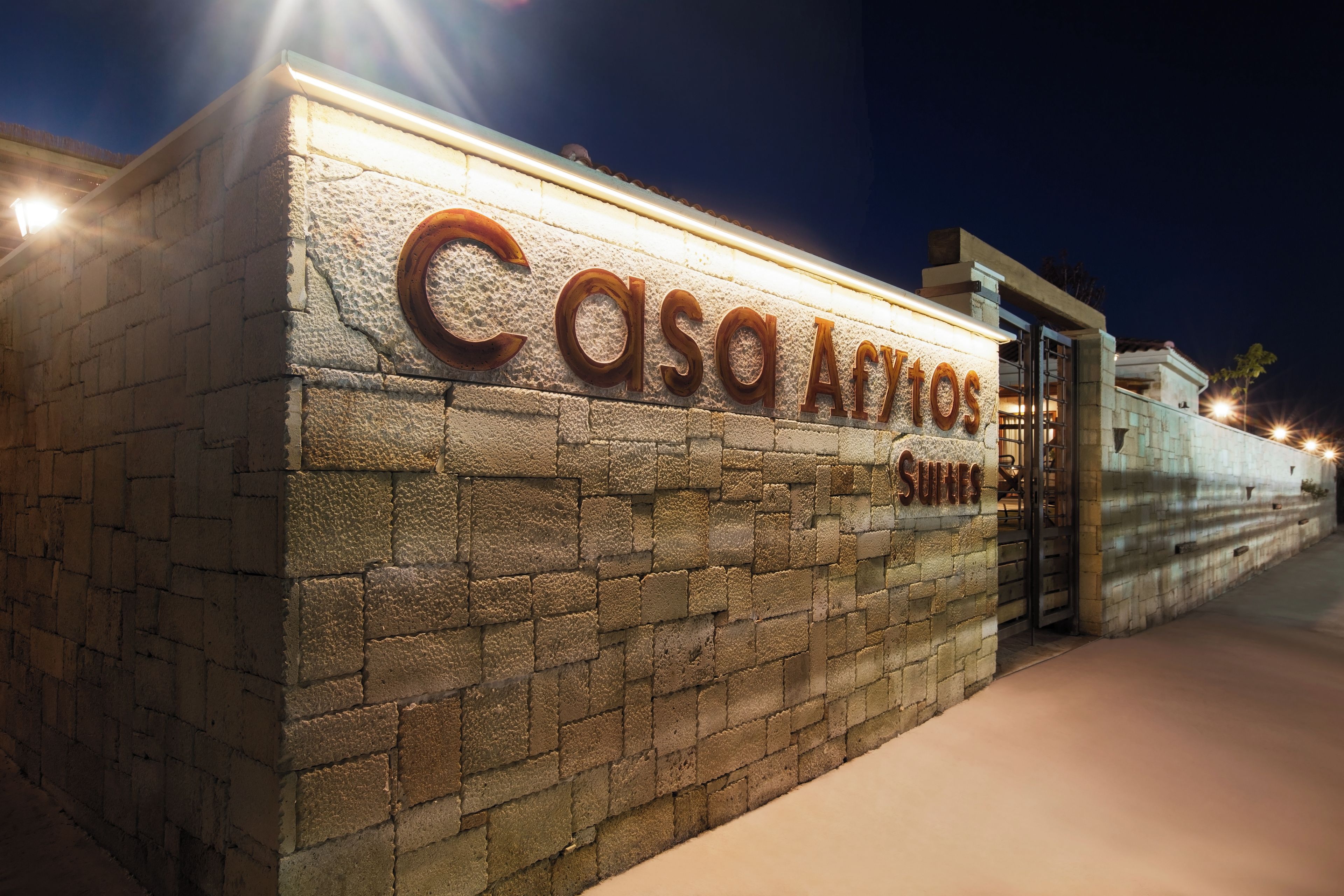 Een stenen muur met de naam 'Casa Afytos Suites' verlicht in de nacht.