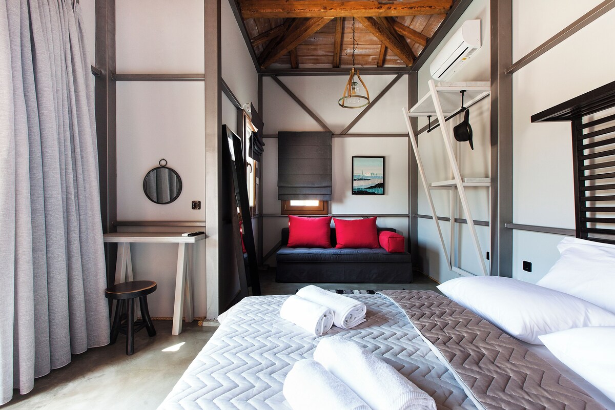 A bedroom with a bed, a desk, a chair, and a window.
