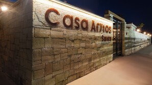 Eine Steinsäule mit der beleuchteten Aufschrift "Casa Afytos Suites" in der Nacht.