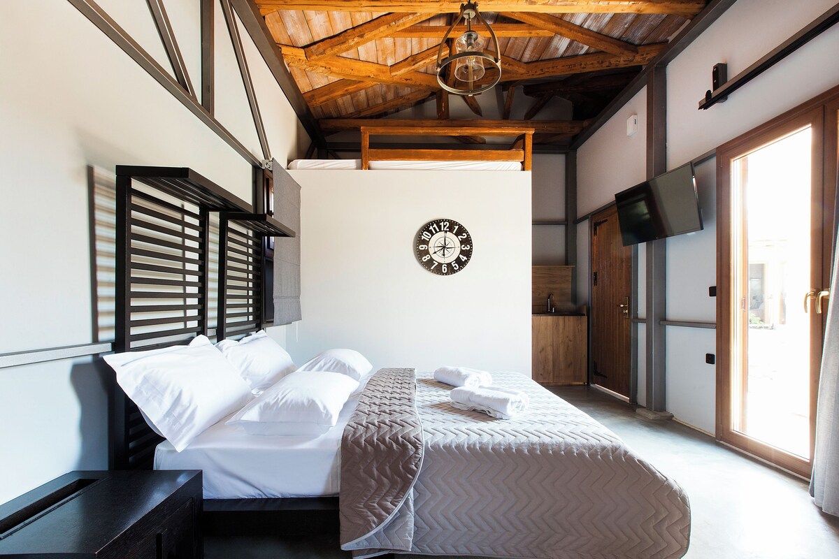 A bedroom with a bed, a clock on the wall, and a television on the wall.