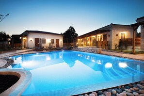A swimming pool with a tiled deck, surrounded by stone walls and wooden fences. - Casa Afytos (Kassandra)