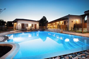 Une piscine dotée d’une plage carrelée, entourée de murs en pierre et de clôtures en bois.
