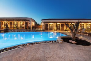A poolside area with a swimming pool, lounge chairs, and a building with multiple doors and windows. - Casa Afytos (Kassandra)