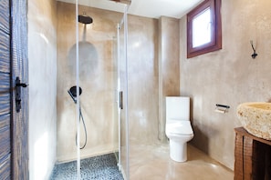 A bathroom with a glass-enclosed shower, a white toilet, and a sink with a stone basin. - Casa Afytos (Kassandra)