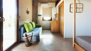 Ein gemütliches Zimmer mit einem blauen Sofa, einer Holzbalkendecke, einer Wanduhr und einem Fenster.