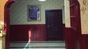 A room with a dark wooden door, a framed sign on the wall, and a chandelier. - Songpan jiaguo senge minsu (Songpan)