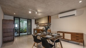 A modern dining area with a wooden table and chairs, a built-in bench, and an air conditioning unit on the wall. - Charming single level apt w terrace and pool access (Mérida)