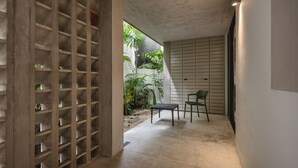 A corridor with a concrete ceiling, a wooden lattice structure, and a small table with chairs. - Charming single level apt w terrace and pool access (Mérida)