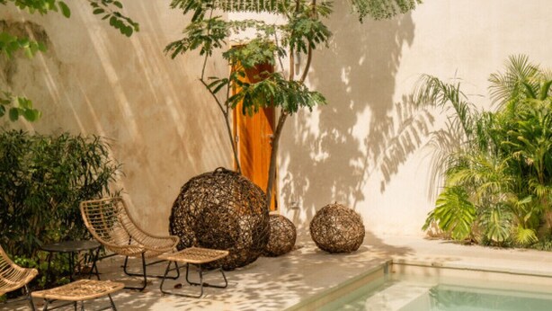 An outdoor pool area with wicker furniture and decorative spherical objects. - Artsy loft with plunge pool and rooftop terrace (Mérida)