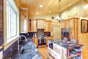 Eine Küche mit Holzausstattung, einer Kochinsel mit Spüle, Herd und Kühlschrank.