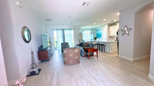 A spacious living area with a sofa, a coffee table, and a decorative Eiffel Tower model. - Modern 10’ Ceiling.Smart devices. 2mi to activities, Easy access i95 & turnpike! (Port St. Lucie)