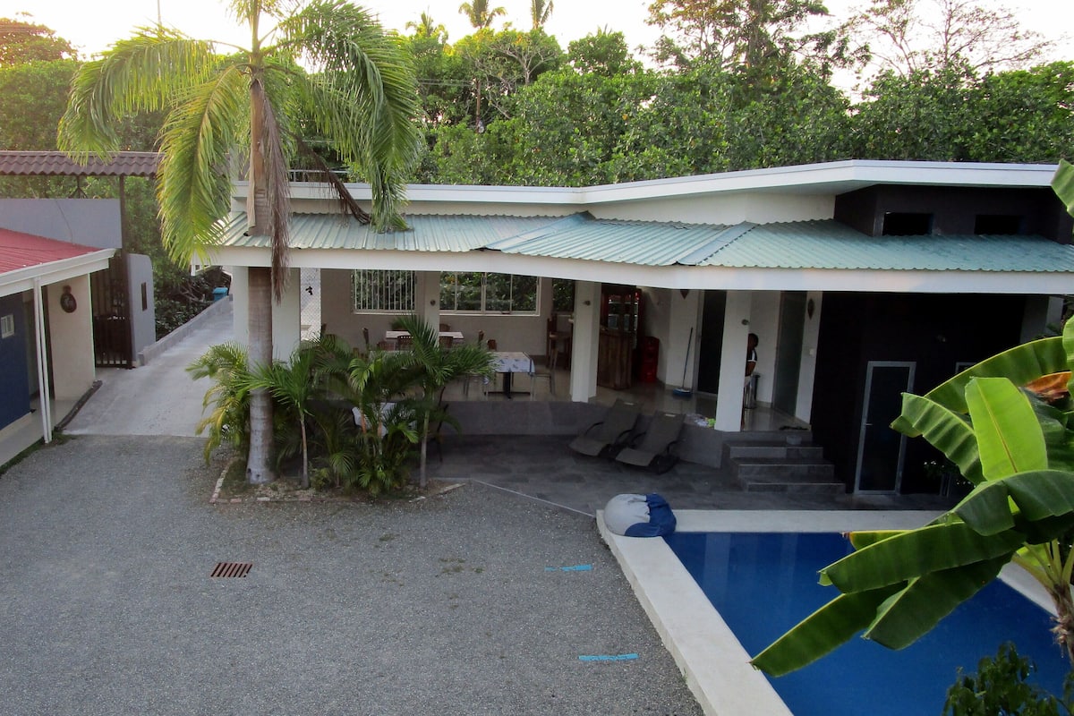 A building with a swimming pool, covered patio, and outdoor seating area.