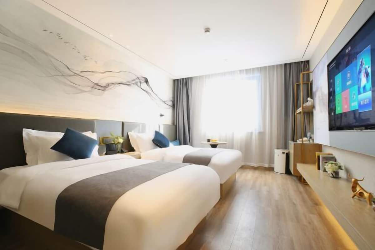 Una habitación de hotel moderna con dos camas, un televisor grande y una decoración minimalista.