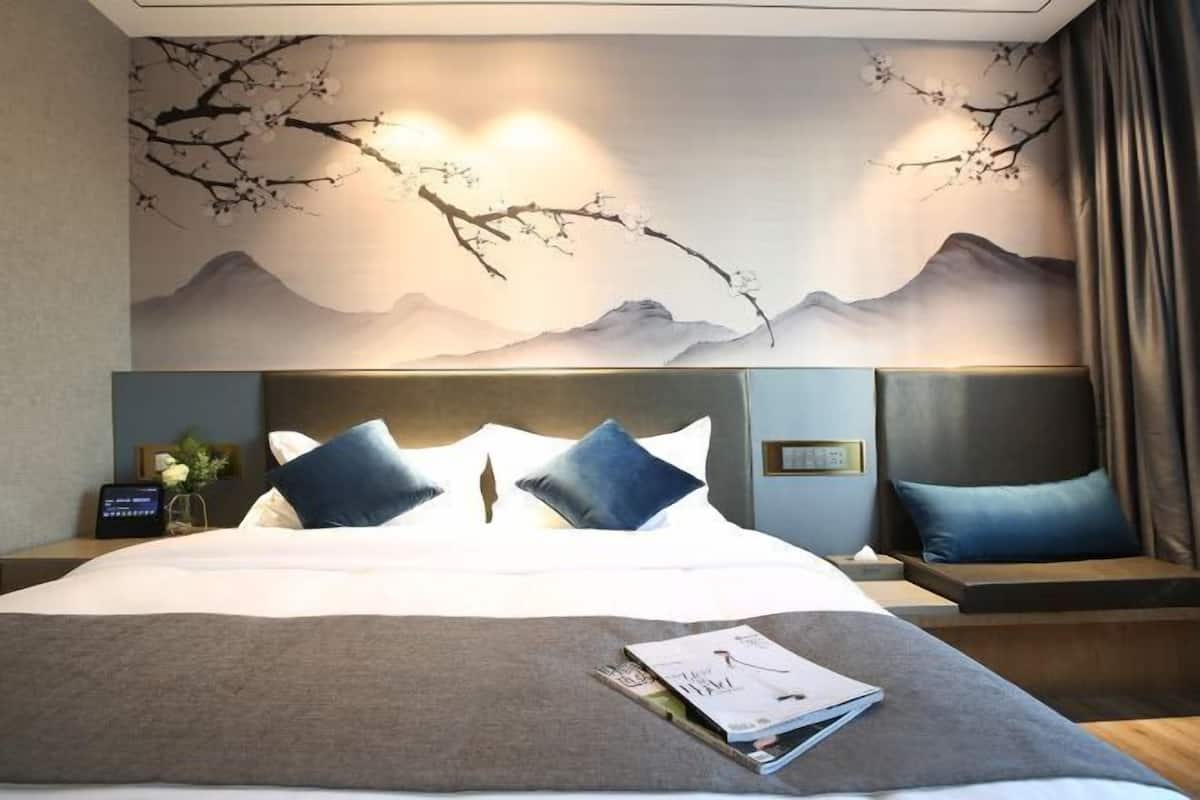 Una habitación de hotel con una cama grande, dos mesitas de noche y un mural en la pared.